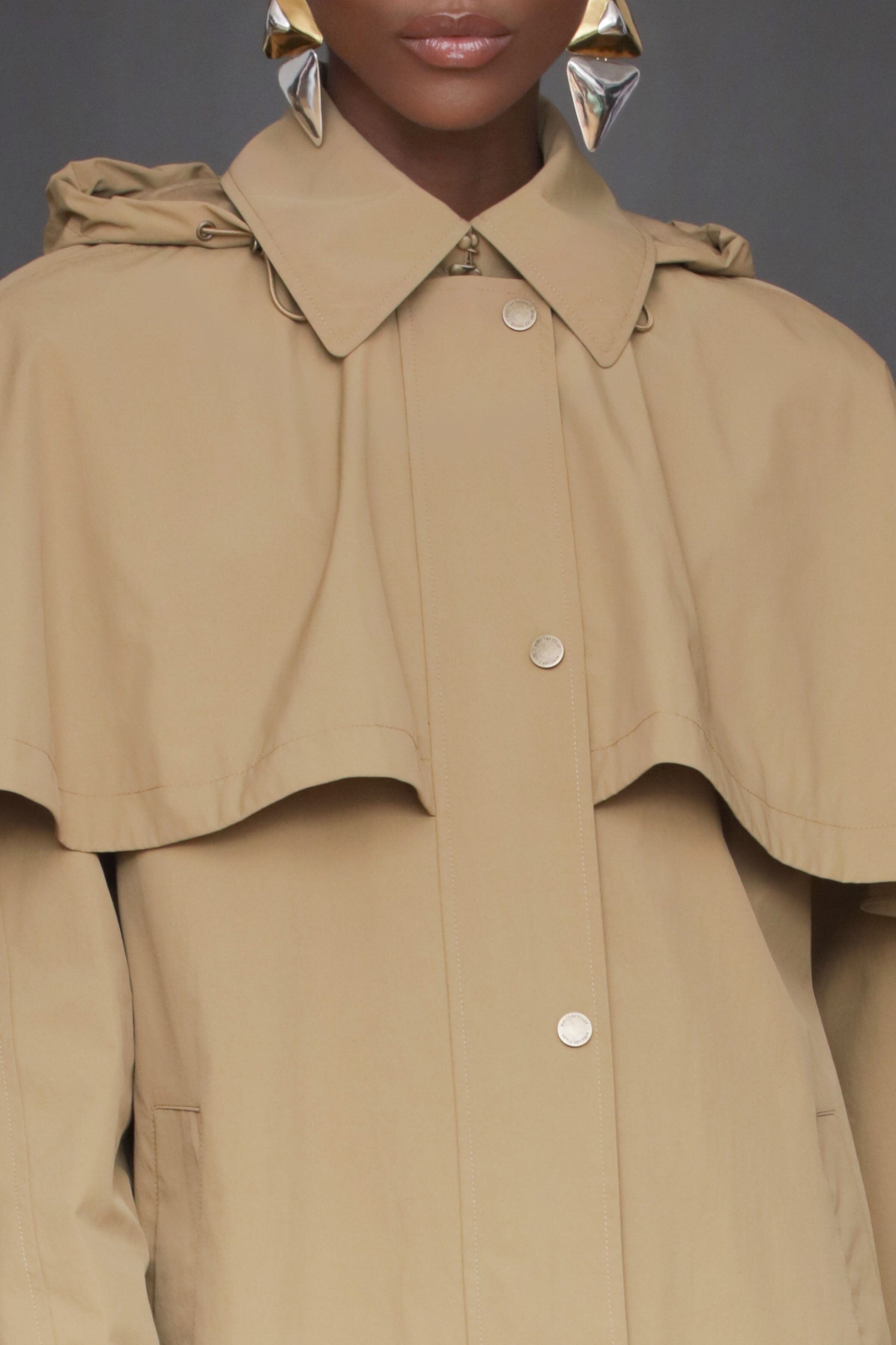 This wheat beige nylon cape raincoat. Oversized silhouette, feminine cape, and snap and zipper closure - Shop women's cape raincoats by Avec Les Filles.