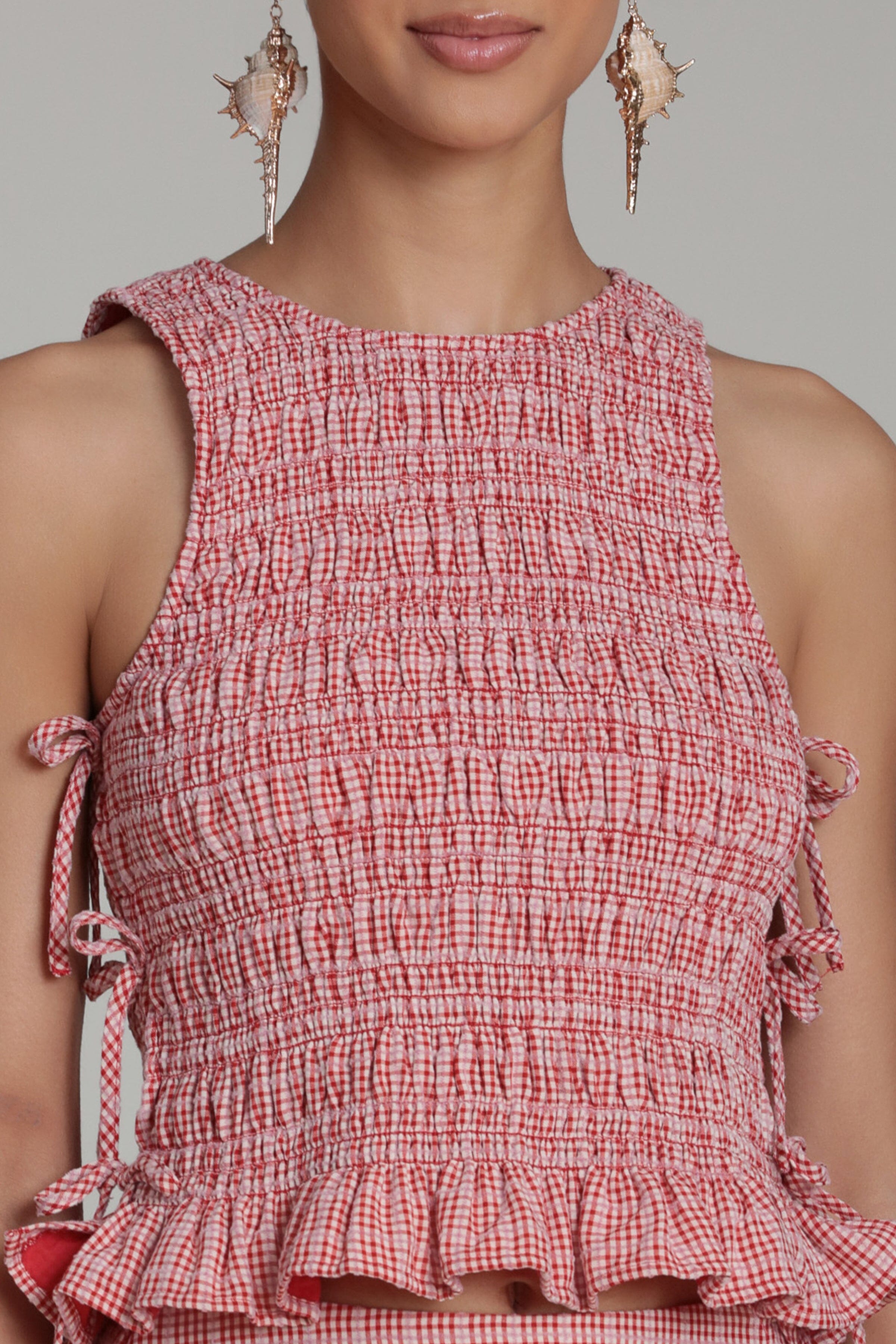 Sleeveless red and white gingham top with crew neck and ruffle hem. Shop women's tank tops by Avec Les Filles.