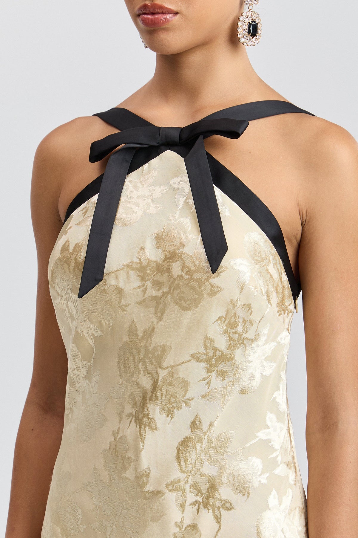 Cream formal maxi dress with black satin straps and a bow neck. Shop women's cute backless dresses by Avec Les Filles.