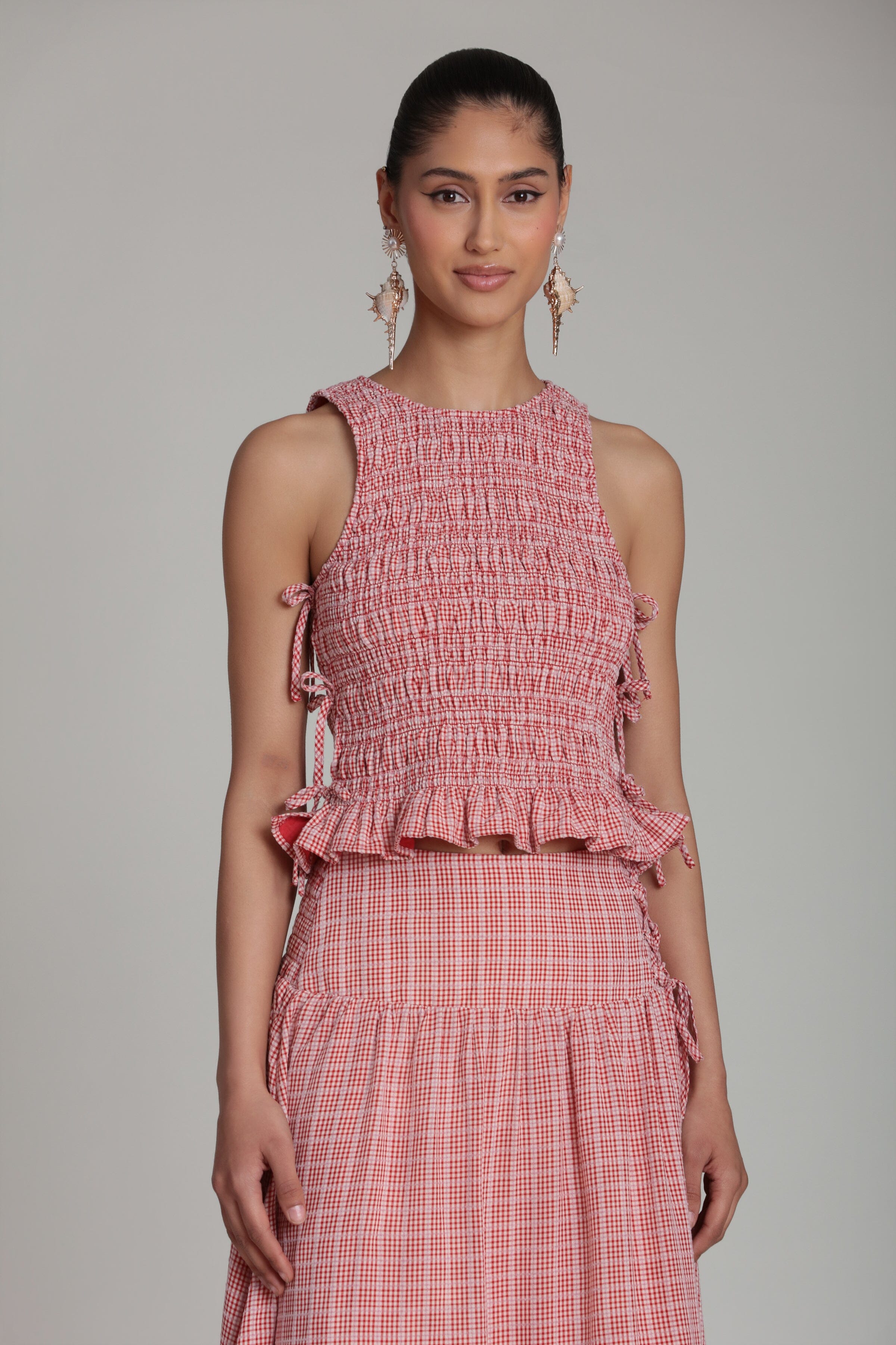 Smocked sleeveless red and white gingham top with crew neckline and ruffle hem by Avec Les Filles.