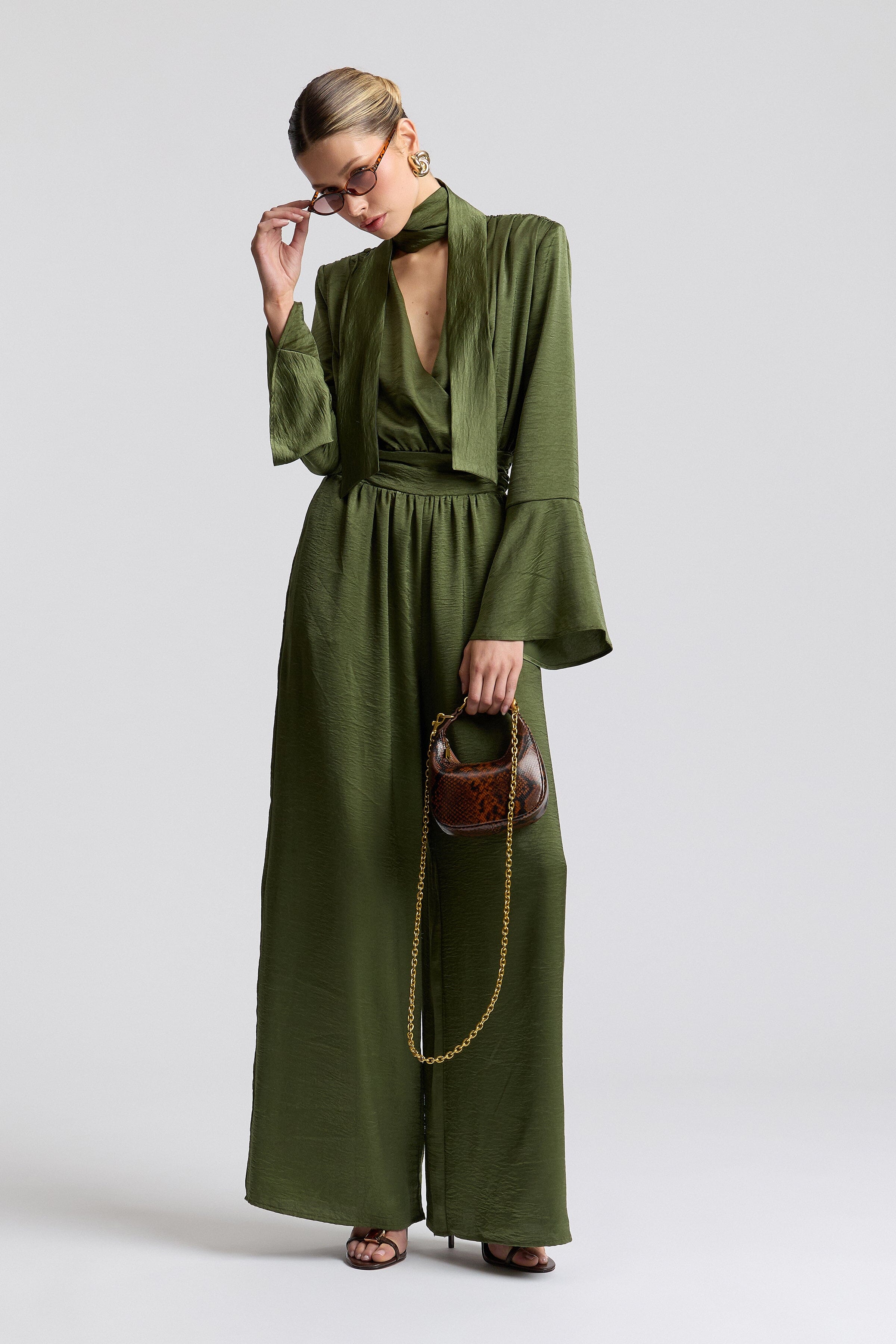 Tie-neck green jumpsuit with high neck and structured square shoulders. Shop cute satin jumpsuits by Avec Les Filles.