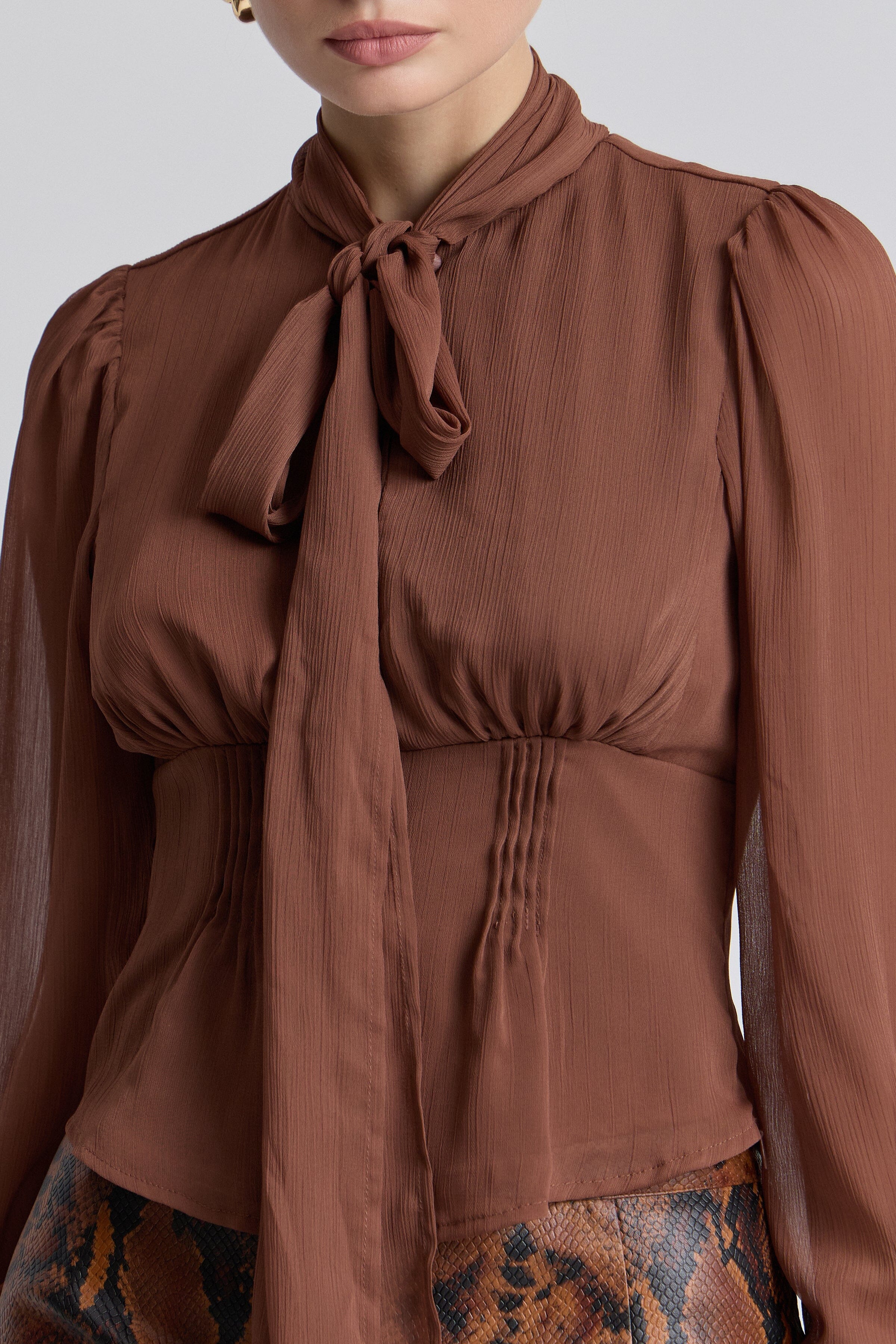 Chiffon tie-neck brown color blouse with long puff sleeves and a faux-button front. Shop women's tops by Avec Les Filles.